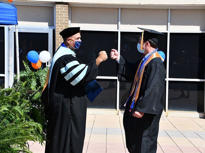 Dr. Poarch offers a fist bump to a graduate